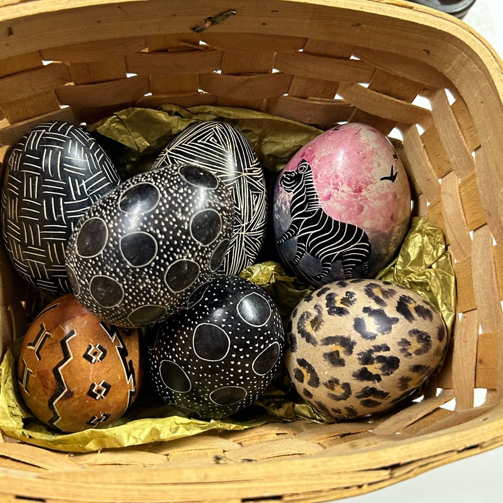 7 hand painted stone eggs in a basket .